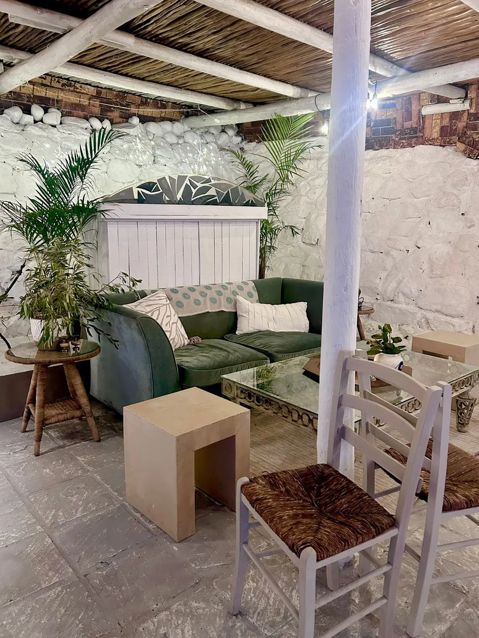 The courtyard lounge at Nostos, with a green sofa and palms