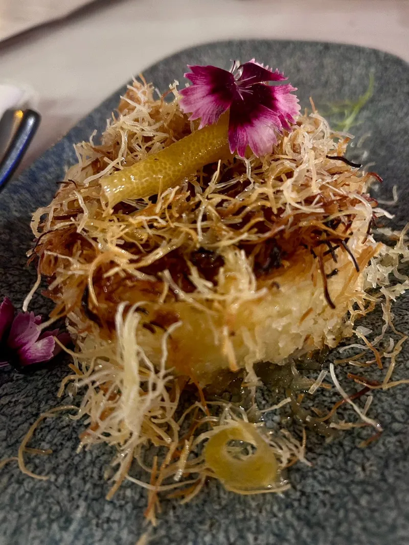 A kataifi dish with lemon and an edible flower