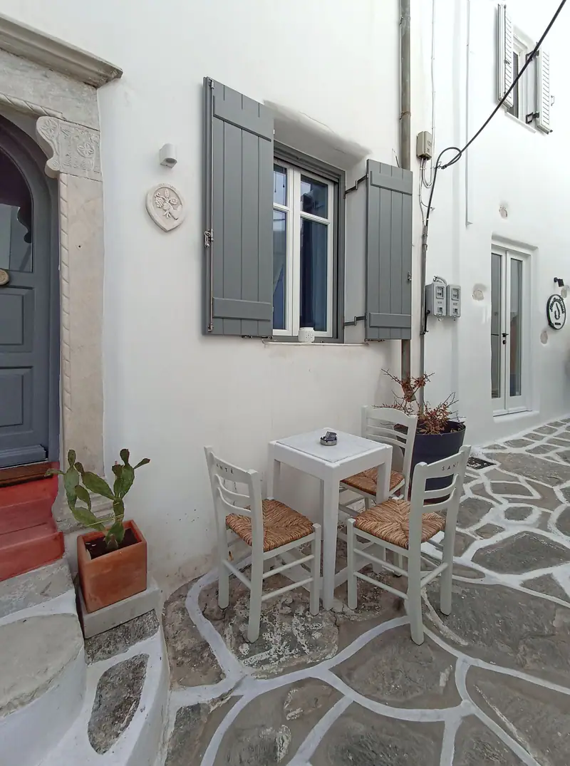 A whitewashed lane with a blue door and pots of flowers